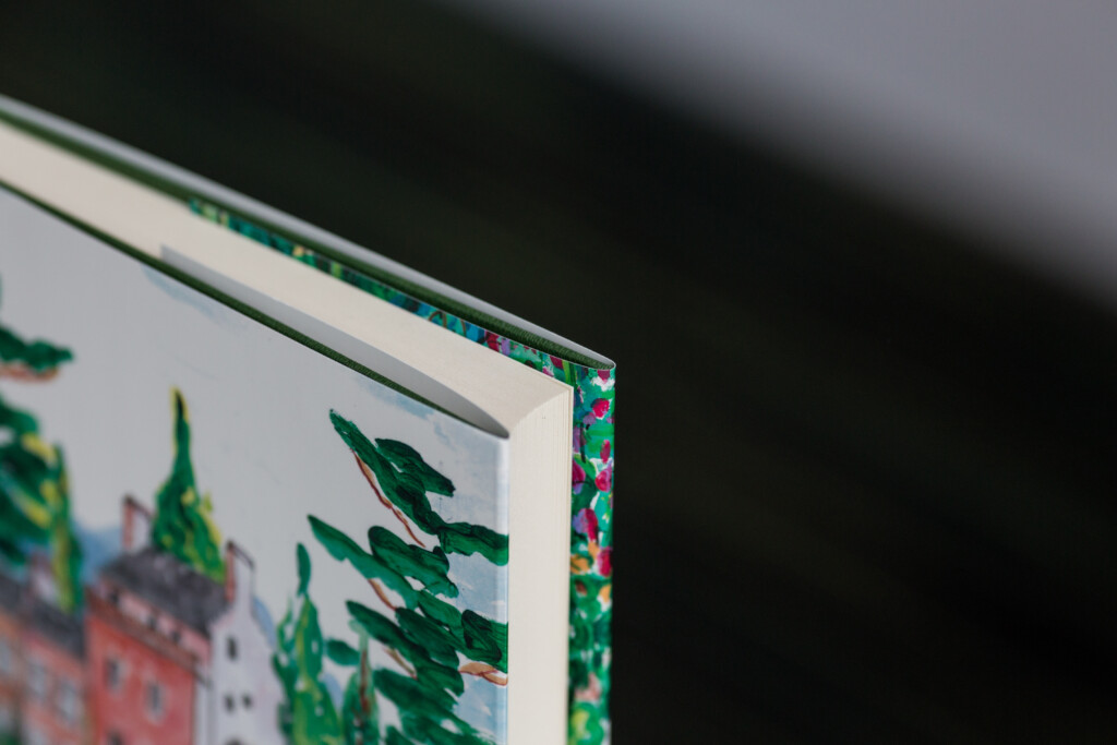 Close-up of hardcover book edge showing green foil stamping detail on spine and cover boards.