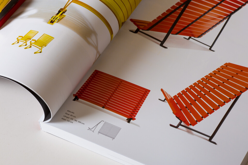 Nola product catalogue open to a page displaying four deck chair designs in yellow, red and orange with black metal frames