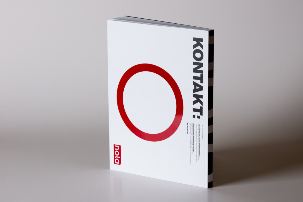 White hardcover book with red circle on cover and KONTAKT text on spine, displayed at angle against neutral background.