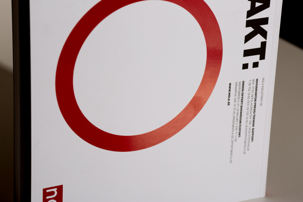 White product catalogue with red circular design element on cover, small red logo at bottom left, and black text along right