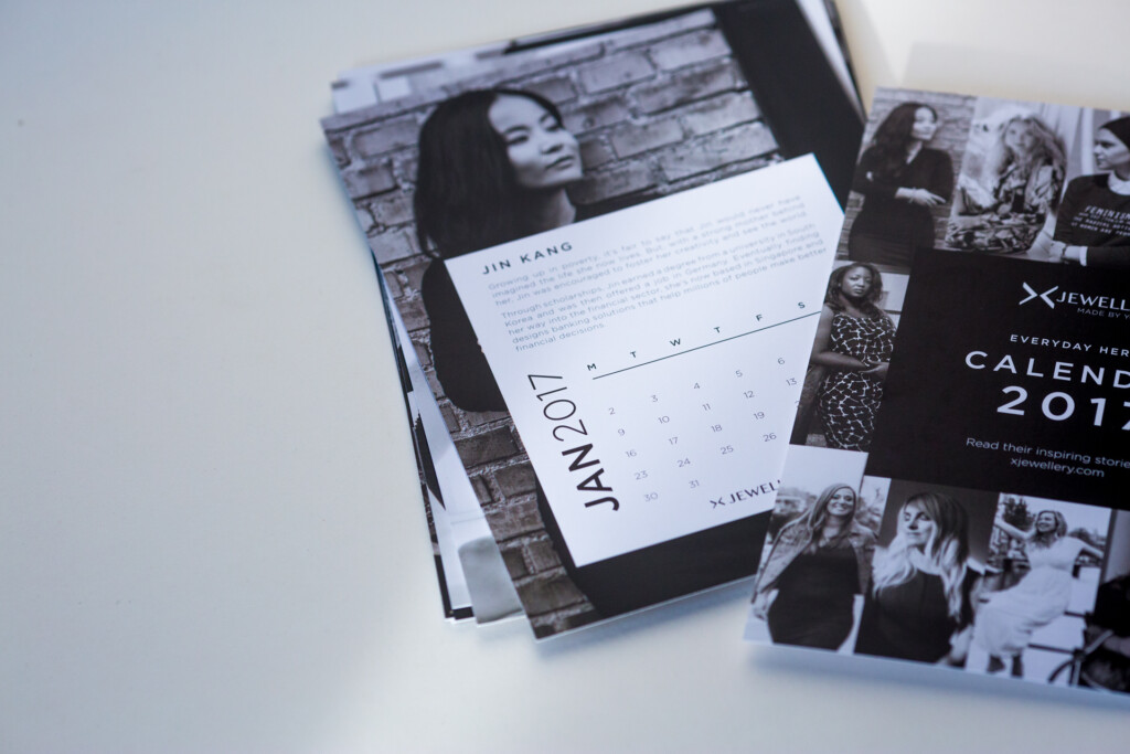 Stack of printed calendars and black and white photograph books displayed fanned out, showing covers and interior pages.