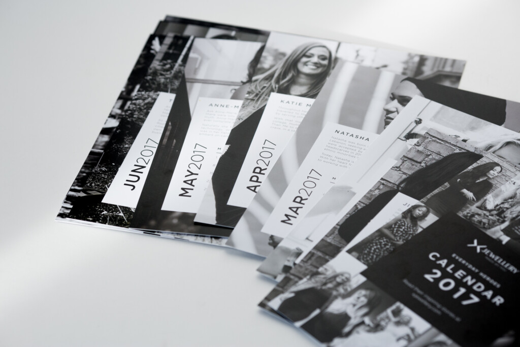 Fanned printed calendars and brochures with black and white photography displayed on white surface