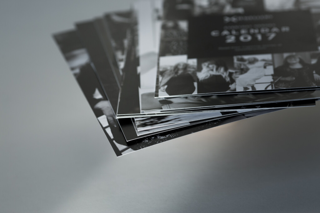 Stack of printed calendars fanned out, showing black and white photography on covers and interior pages.