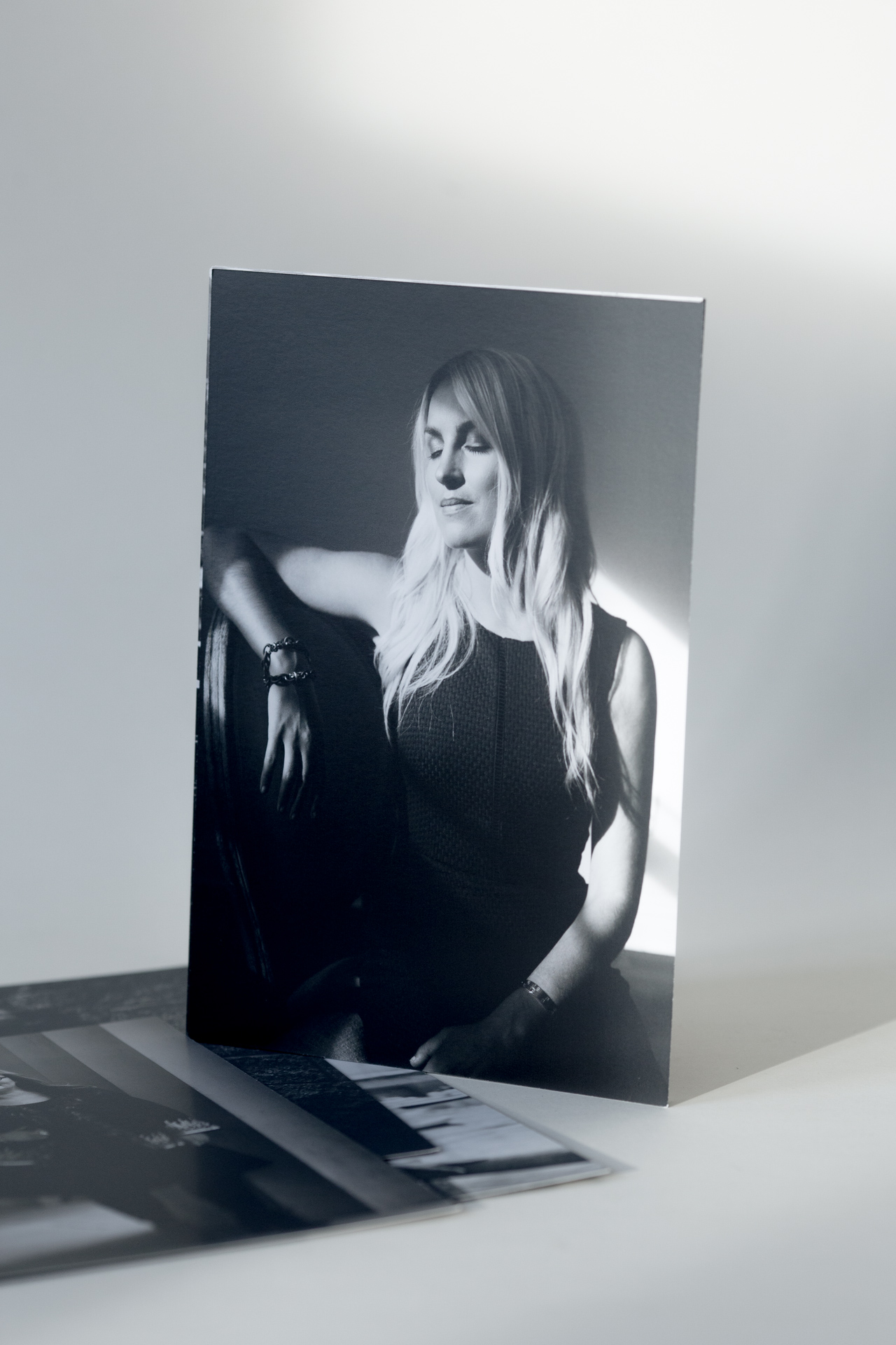Black and white portrait photograph printed on card stock, displayed standing upright with additional prints fanned beneath.