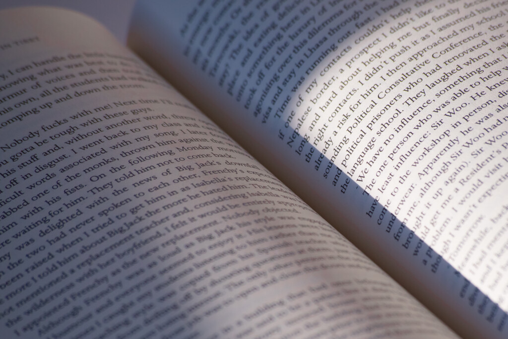 Opened paperback book showing printed text pages with soft shadow across the pages.