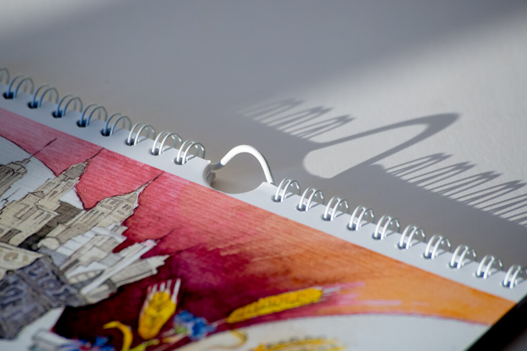 Printed wall calendar with colourful floral design and white spiral binding, displayed against a ruler.