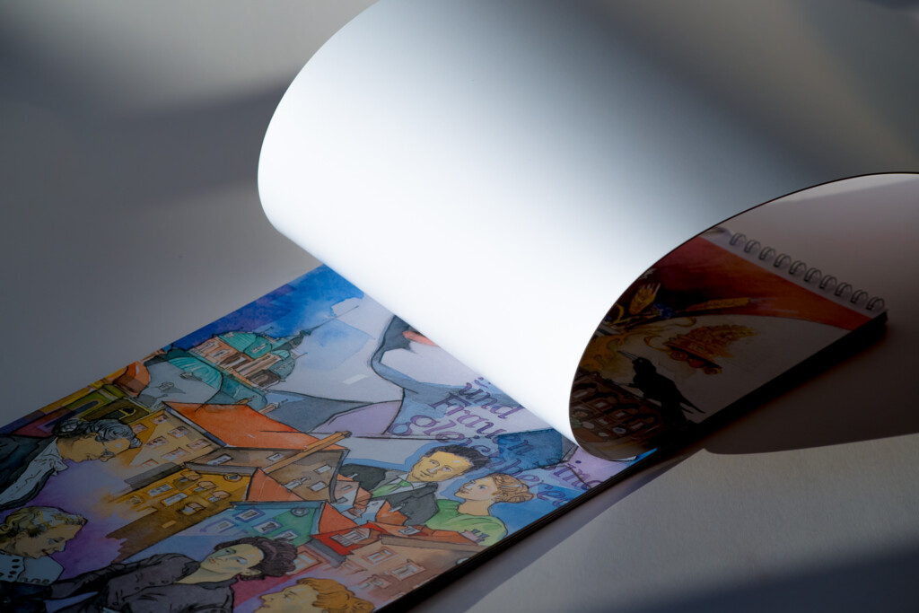 Colourful illustrated wall calendar with gloss lamination being unrolled to reveal the printed spread.