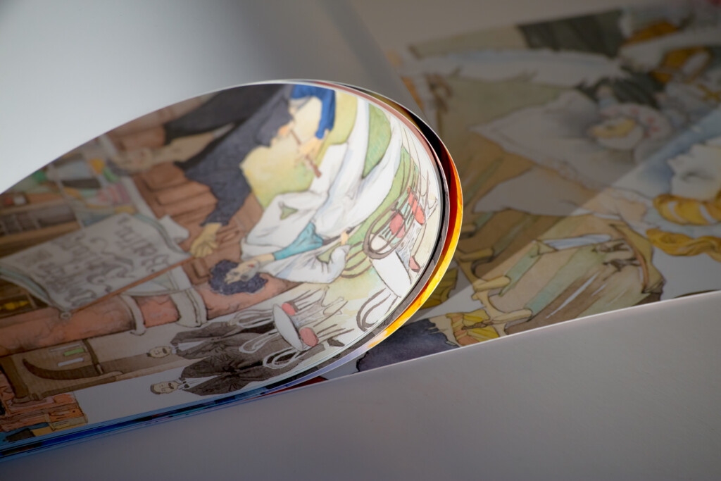 Rolled wall calendar with glossy laminated cover featuring illustrated figures, displayed against printed calendar pages.
