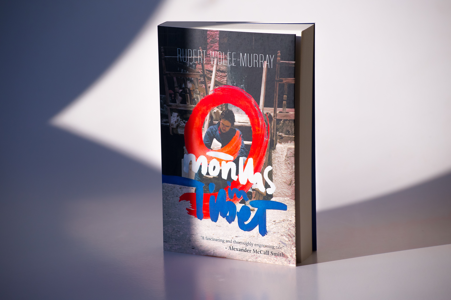 Paperback book with red and white graphic design on cover, shown standing against neutral background with soft shadow.