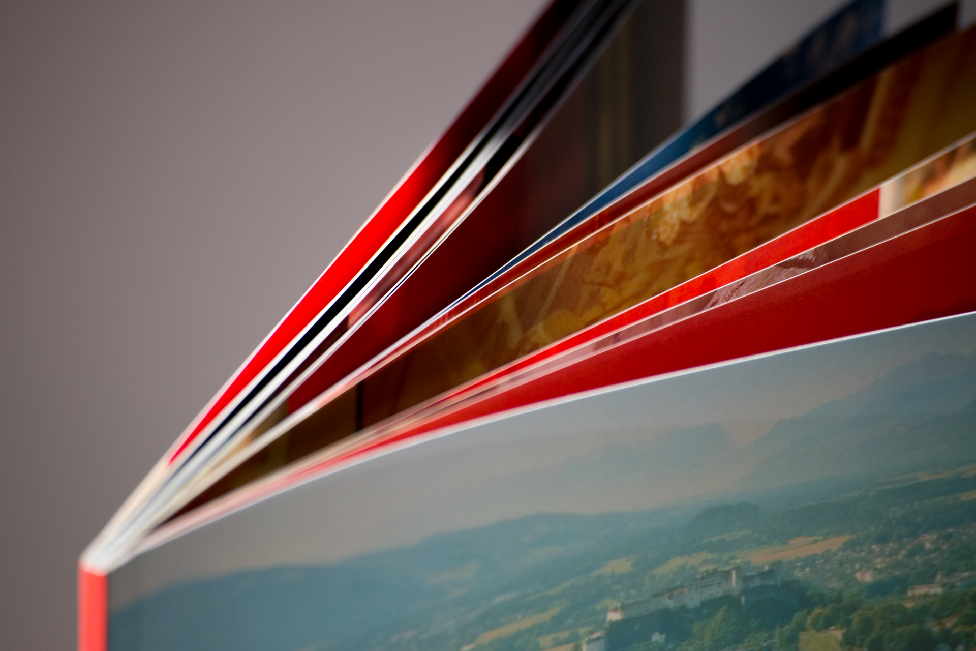 Stack of softcover books fanned out showing coloured spines and pages with landscape photograph on cover.
