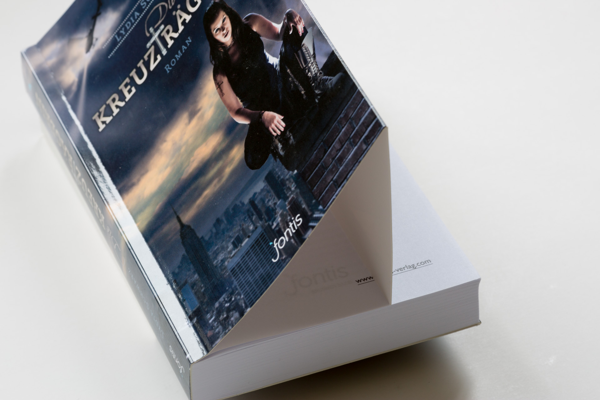 Hardcover book titled Kreuztragerin in a white slipcase, displayed at an angle showing the cover featuring a woman in dark