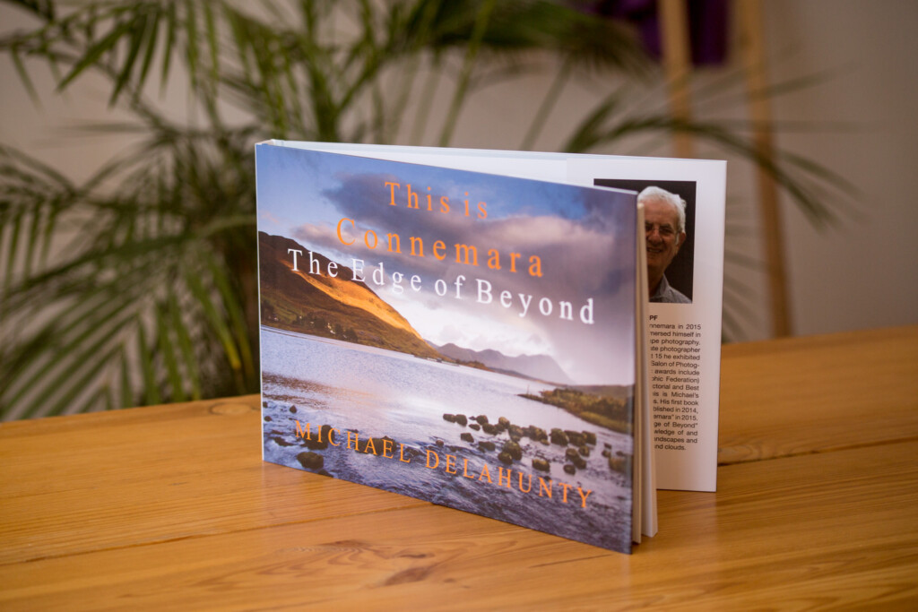 Hardcover book titled "This is Connemara The Edge of Beyond" displayed open on wooden table with plant in background