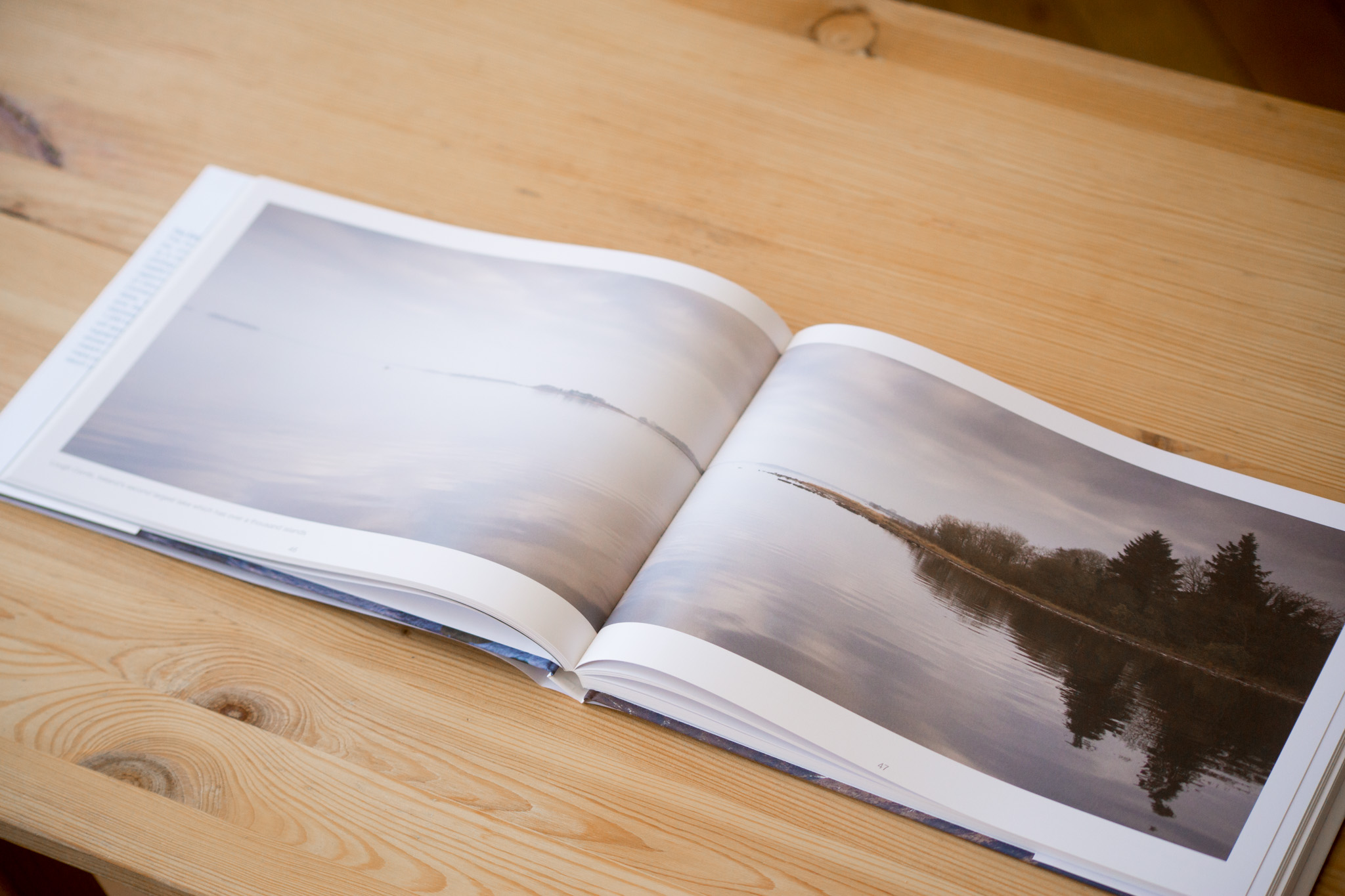 Opened photo album with landscape photographs printed across two pages, displayed on wooden surface.