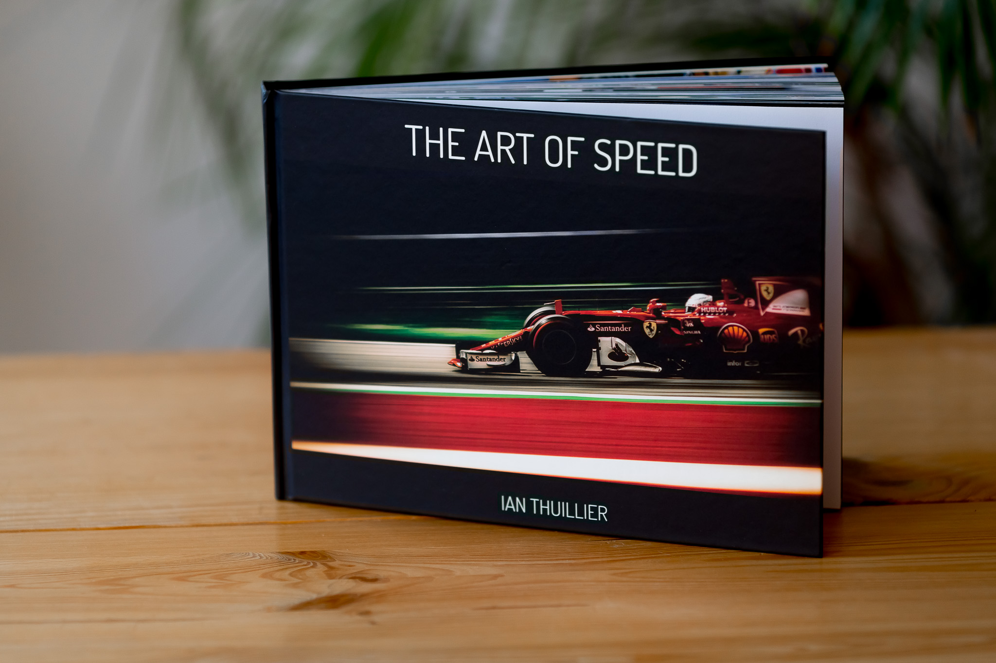 Hardcover book titled "The Art of Speed" by Ian Thuillier featuring a red Formula 1 car on dark cover, displayed on wooden