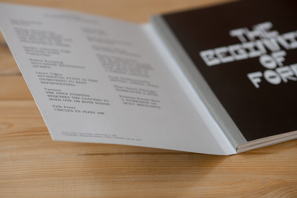 Open softcover book with Swiss binding, linen spine, showing table of contents and cover with white text on dark background.