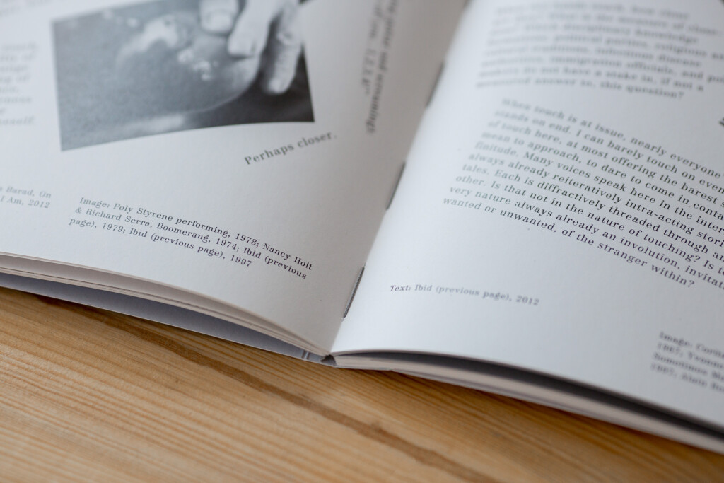 Open softcover book with linen spine showing text pages and a black and white photograph, displayed on wooden surface.