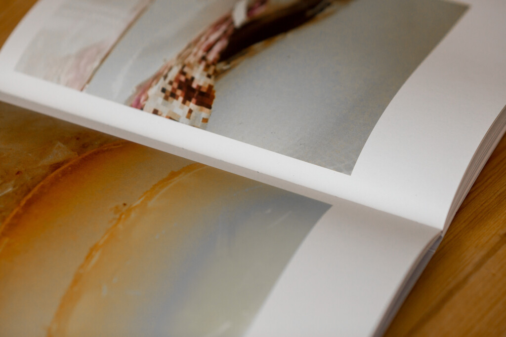 Swiss binding softcover book with linen spine detail, open pages on wooden surface.