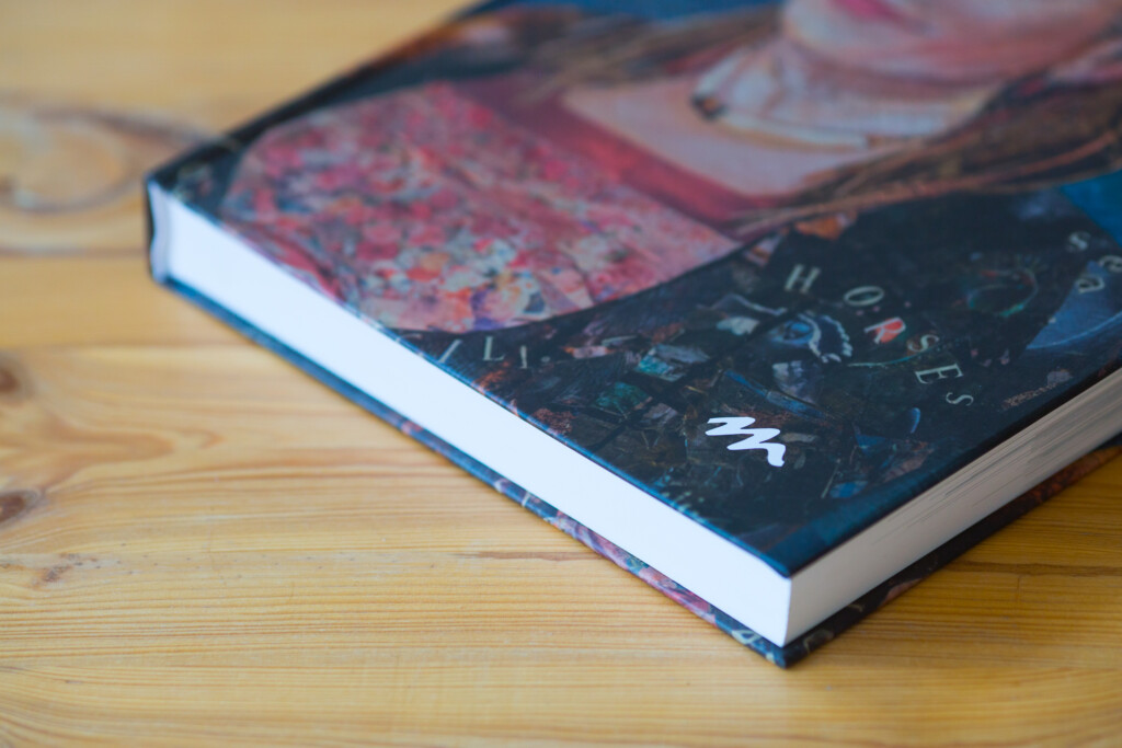 Hardcover book with colourful abstract cover design and dark navy spine, displayed on wooden surface.