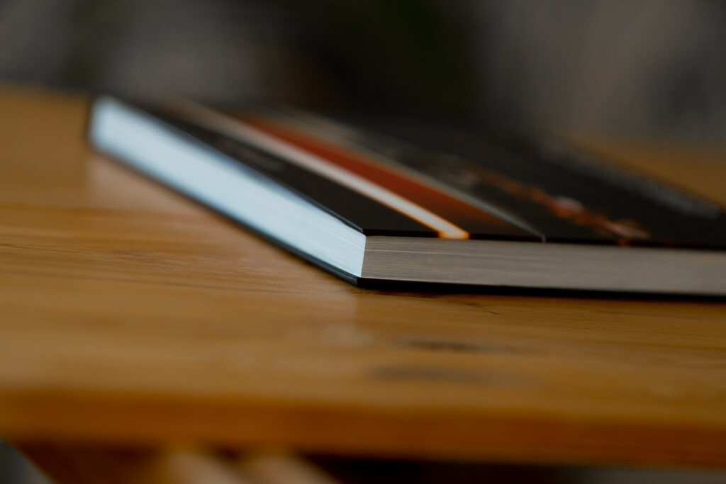Hardcover books with white and dark spines stacked on wooden surface, showing binding detail.