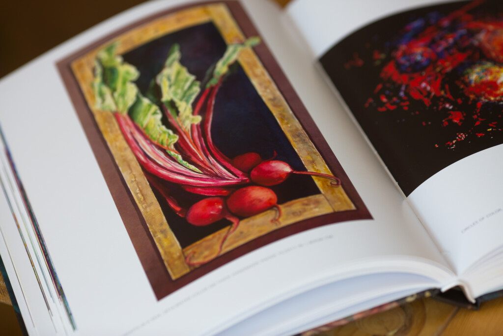 Open hardcover book showing an illustration of red radishes with green leaves on a dark background within a gold-bordered