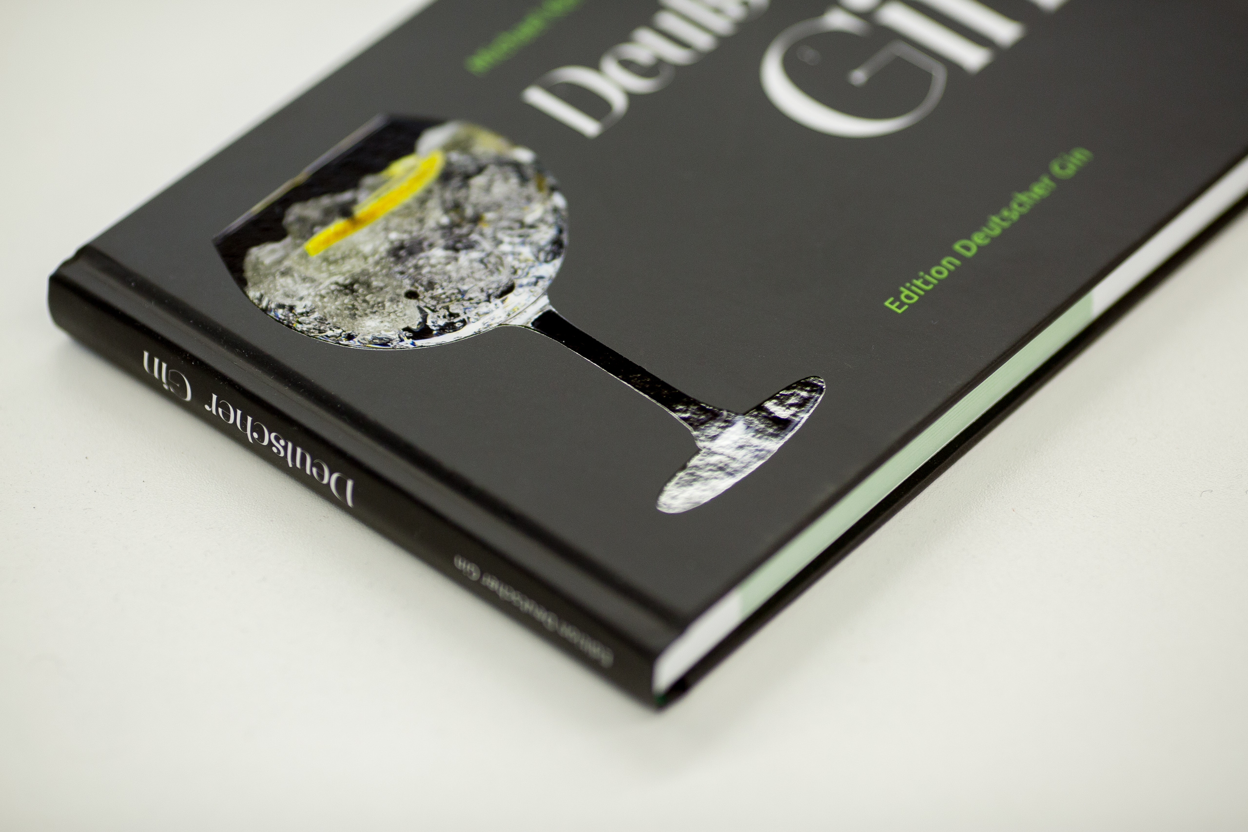 Hardcover book with black cover featuring a cut-out window revealing a textured grey surface with yellow accent and a boat