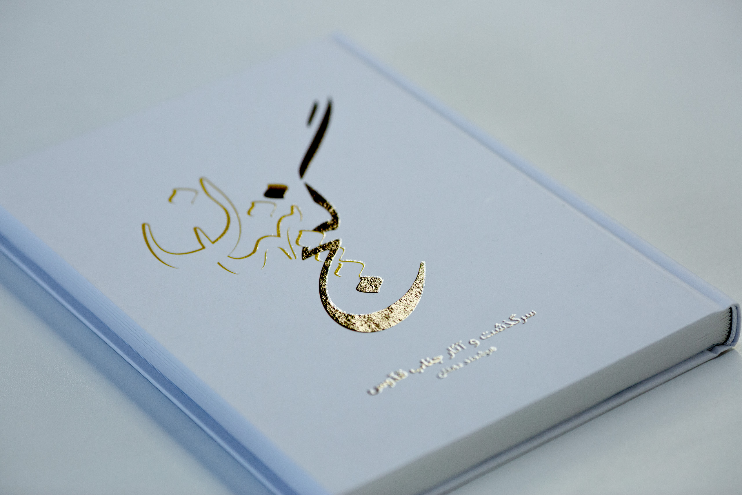 Case-bound book with gold and black foil-stamped Arabic script on light blue cover.