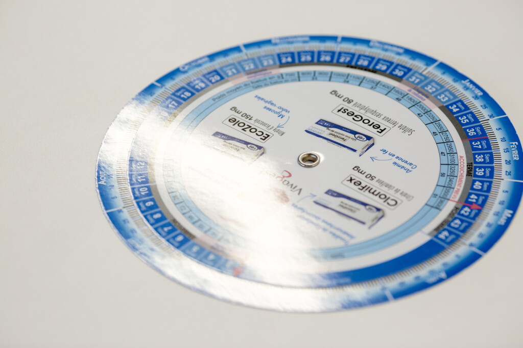Circular pregnancy calendar disc with blue numbered outer ring and white centre, printed with month and date information.