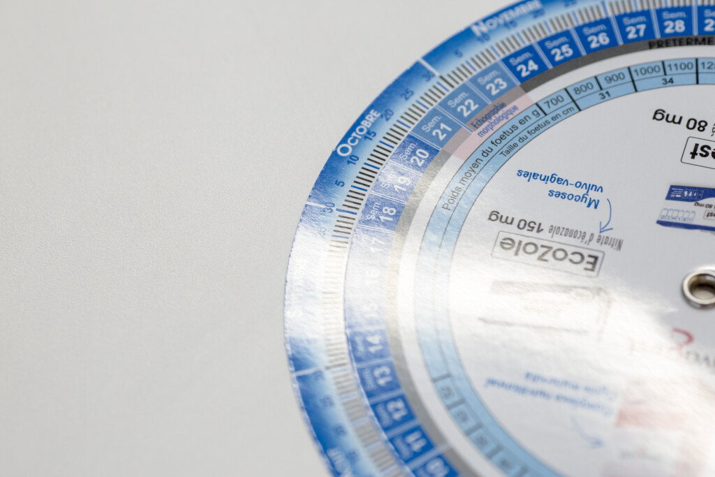 Blue and white pregnancy calendar disc with concentric rotating wheels showing dates and calculations.