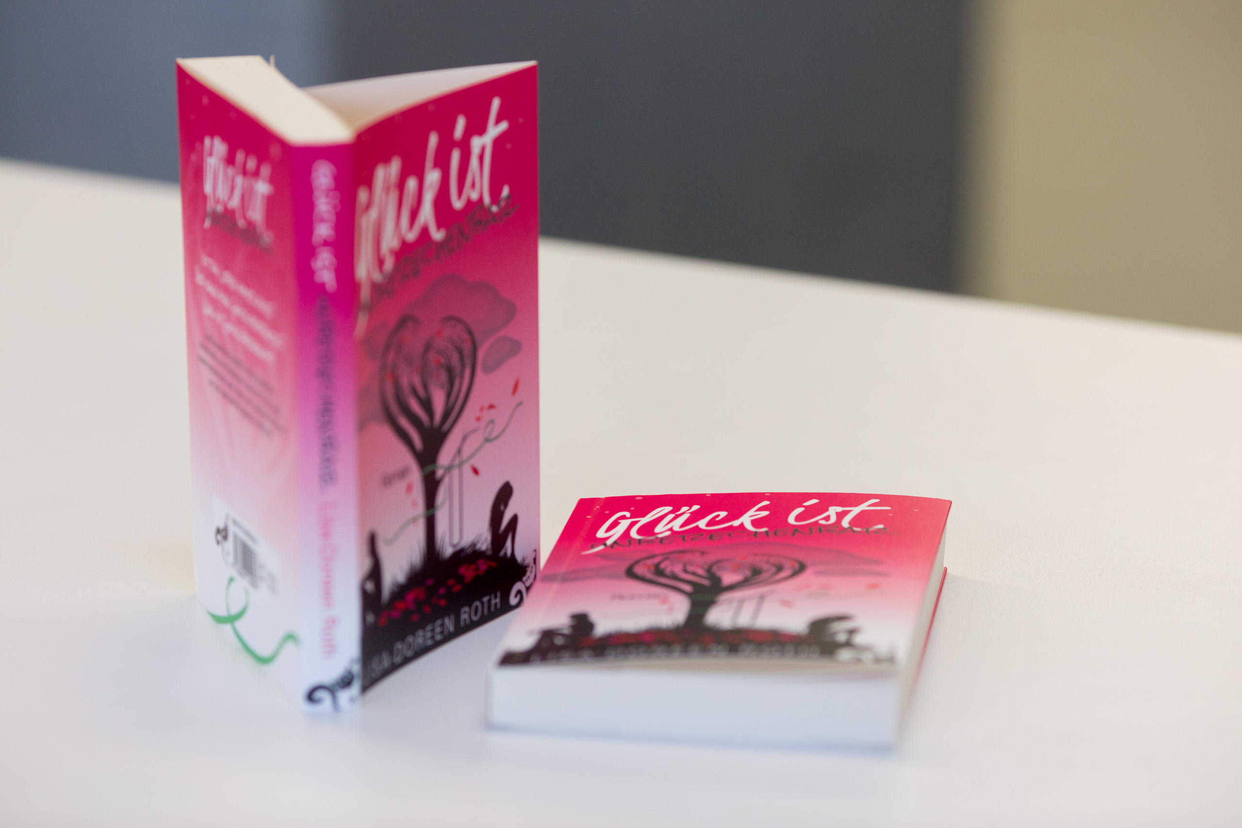 Softcover book with flaps featuring pink gradient cover and stylised tree imagery, displayed with matching promotional card.
