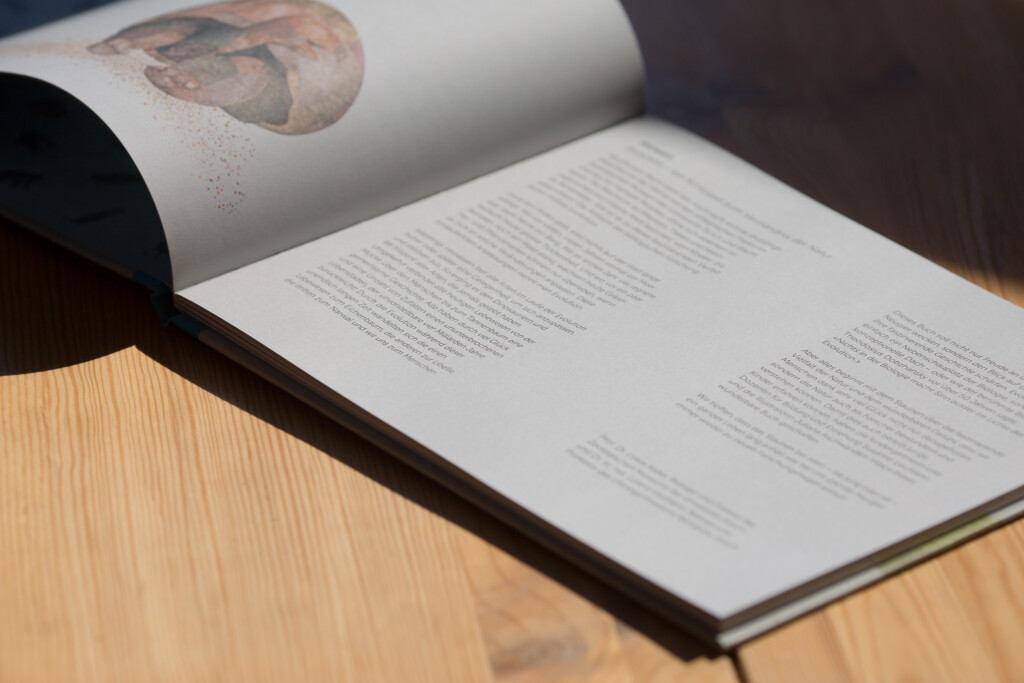 Open hardcover cookbook showing text pages with an illustrated cover visible on the rolled back dust jacket.
