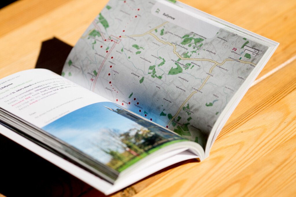 Open softcover guide showing colour landscape photograph on lower spread and map with green areas and red markers on upper