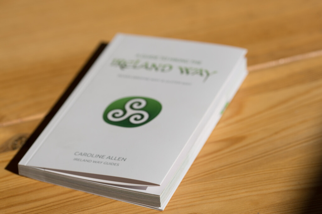 Softcover book with green spiral logo on white cover, displayed on wooden surface.