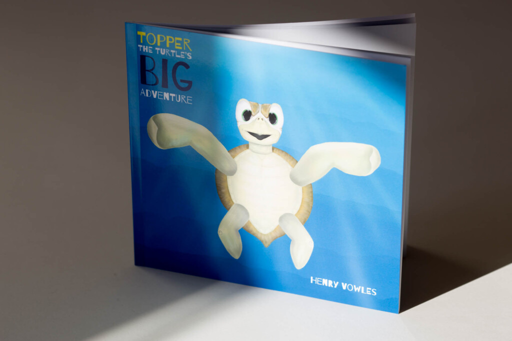 Hardcover children's book with blue cover featuring white cartoon character, titled "Toppes the Turtle's Big Adventure" by