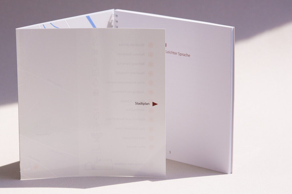 Open spiral-bound book with wire-o binding and internal pages printed with German text.