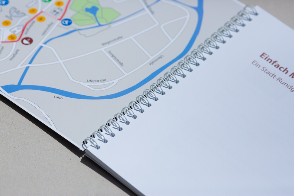 Spiral-bound notebook with city map visible on open page, showing blue wire-o binding detail.