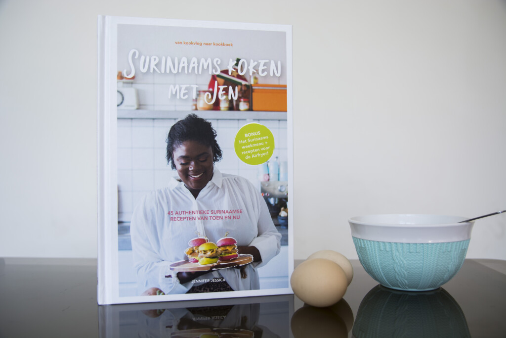 Hardcover cookbook displayed with turquoise ceramic bowl and eggs, showing chef on cover and food photography on pages.