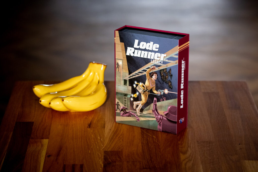 Lode Runner game box with red slipcase displayed next to fresh yellow bananas on wooden surface.