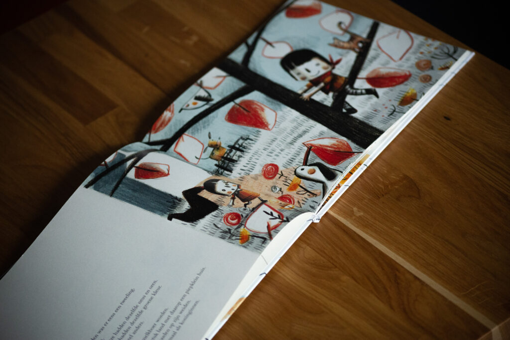 Hardcover children's book spread open on wooden surface showing illustrated pages with characters and red balloon motifs